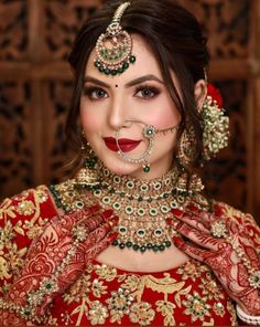 a woman wearing a red and gold outfit with jewelry on her neck, nose ring and necklace