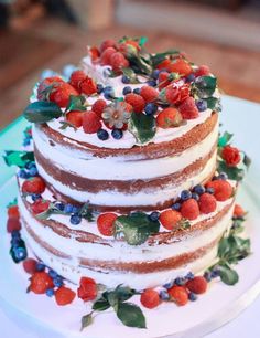 a three layer cake with berries and leaves on top