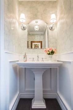 a white pedestal sink sitting under a bathroom mirror