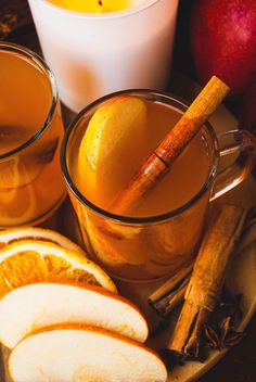 two mugs filled with apple cider and cinnamon sticks