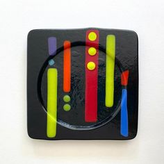 a black plate with multicolored lines on it and a toothbrush in the middle