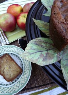 there is a piece of cake on the plate next to some apples and a fork