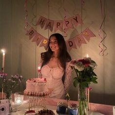 a woman standing in front of a birthday cake with candles on it and decorations around her