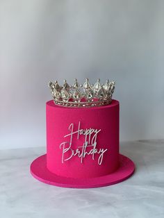 a pink birthday cake with a tiara on top and happy birthday written on it