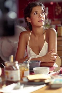 a woman sitting at a table with food in front of her and looking off to the side