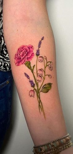 a woman's arm with pink flowers on it and green leaves in the middle