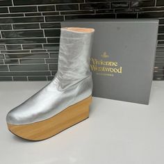 This Is A Gorgeous Pair Of Vivienne Westwood Metallic Silver Calfskin Leather Rocking Horse Mid-Calf Boots Featuring Unique Wooden Platform Block Heel, Round Toes, And Inner Side Zip Closure. Designer: Vivienne Westwood Size: Uk 6, Us 8 Platform: 2.85" Material: Calfskin Leather Color: Metallic Silver Item Condition: Pre-Owned: Good. Exterior: Good. Moderate Signs Of Wear On Leather Throughout, Scuff On Left Shoe At Toe, Scuffs And Wear At Toes, Small Marks On Leather On Both Shoes At Back Heel, Wear And Some Marks On Wooden Platform. Light Wear On Soles. Interior: Very Good. Moderate Signs Of Wear. Note: Comes With Original Box & 2 Dustbags. Adore The Couture Would Like For Our Customers Vivienne Westwood Shoes, Platform Block Heels, Rocking Horse, Calf Boots, Mid Calf Boots, Platform Boots, Vivienne Westwood, Mid Calf, Side Zip