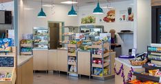 the inside of a grocery store with lots of food on shelves and lights hanging from the ceiling