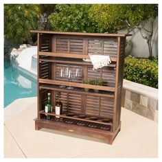 a wooden shelf with wine glasses and bottles on it next to a swimming pool that says convene pub set