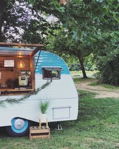 an old camper converted into a mobile home with the door open and plants growing out of it