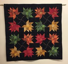 a quilted wall hanging on the side of a wall with autumn leaves in it