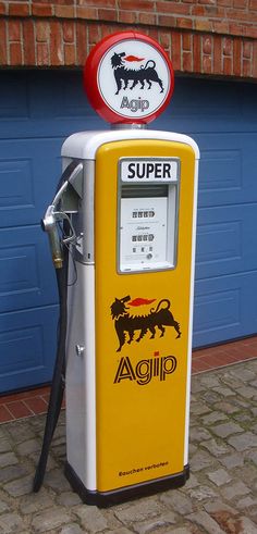 a yellow and white gas pump sitting in front of a blue garage door next to a brick wall