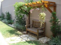 a wooden bench sitting under a pergolated trellis next to a wall with flowers on it