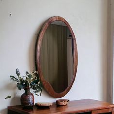 a wooden table with a vase and mirror on it