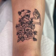 a black and white tattoo on the leg of a woman's arm with flowers