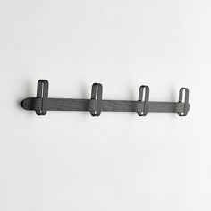 a metal hook on the side of a white wall with three black hooks hanging from it's sides