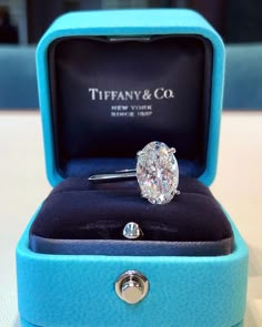 a diamond ring in a blue box on a white table with the words tiffany & co