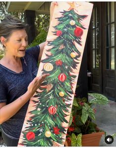 a woman is painting a christmas tree with acrylic paint on the outside of it