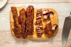 bacon strips on a wooden cutting board next to a knife