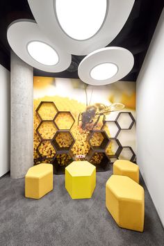 an office with yellow stools and honeycombs painted on the wall behind them