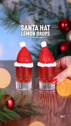 two small cups with strawberries in them on a table next to a christmas tree