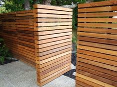 two wooden privacy screens sitting next to each other on a sidewalk with trees in the background