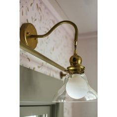 an old fashioned brass wall light with a clear glass shade hanging from it's arm