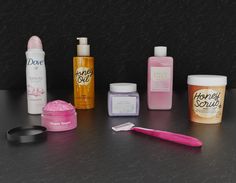 various beauty products are arranged on a counter top with a pink toothbrush and other items