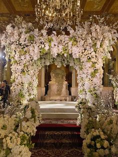 an elaborate wedding ceremony setup with white flowers and greenery on either side of the altar