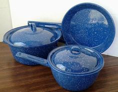 three blue pots and pans sitting on top of a wooden table