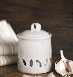 a garlic bulb next to a white ceramic container