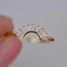 a close up of a person's hand holding a gold ring with five stones