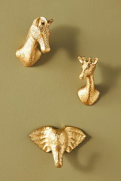 three gold giraffes and a zebra are on the wall next to each other