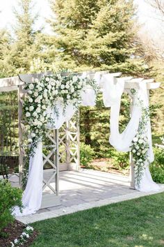 an outdoor wedding ceremony setup with white flowers and greenery on the side of the aisle