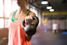 a woman in an orange tank top holding a black kettle