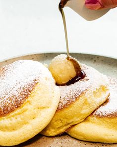 powdered sugar being drizzled on top of pastries in a plate