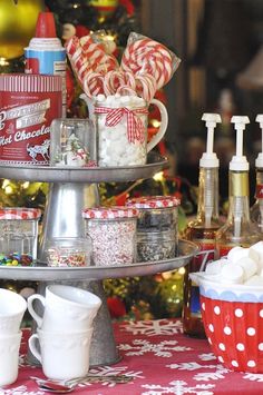 a three tiered tray filled with candy canes and other holiday treats next to a christmas tree