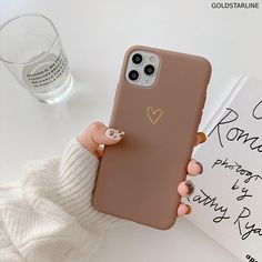 a woman holding up her phone case with a heart sticker on it