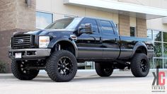 a large black truck parked in front of a building