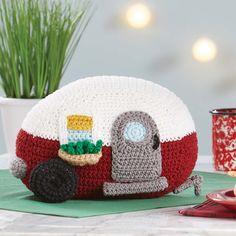 a crocheted camper pillow sitting on top of a table next to a cup