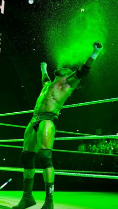 the wrestler is throwing green powder into the air