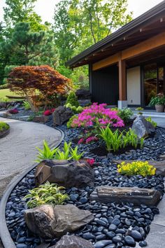 a garden with rocks and flowers in front of a house