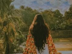 a woman standing in front of a palm tree looking out at the water and trees