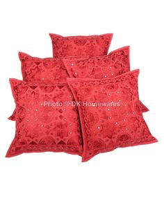 four red pillows with an embroidered design on the front and back, all in different colors