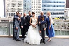 a group of people standing next to each other on top of a bridge in front of tall buildings