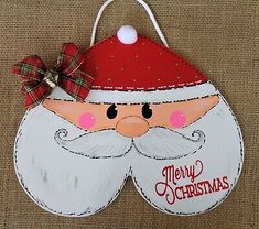 a wooden ornament with a santa clause on it's face and a bow