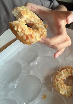 a person is holding up a doughnut in an ice tray with other donuts