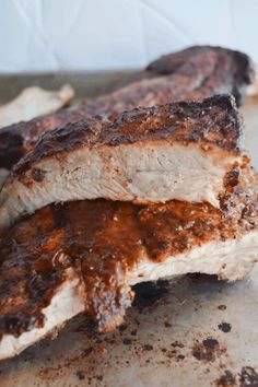 two ribs covered in bbq sauce sitting on top of a counter next to another piece of meat