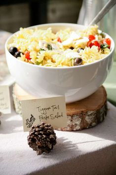 a white bowl filled with pasta next to a pine cone