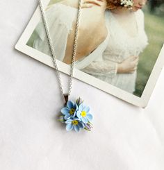 a necklace with a flower on it sitting next to an image of a woman wearing a wedding dress